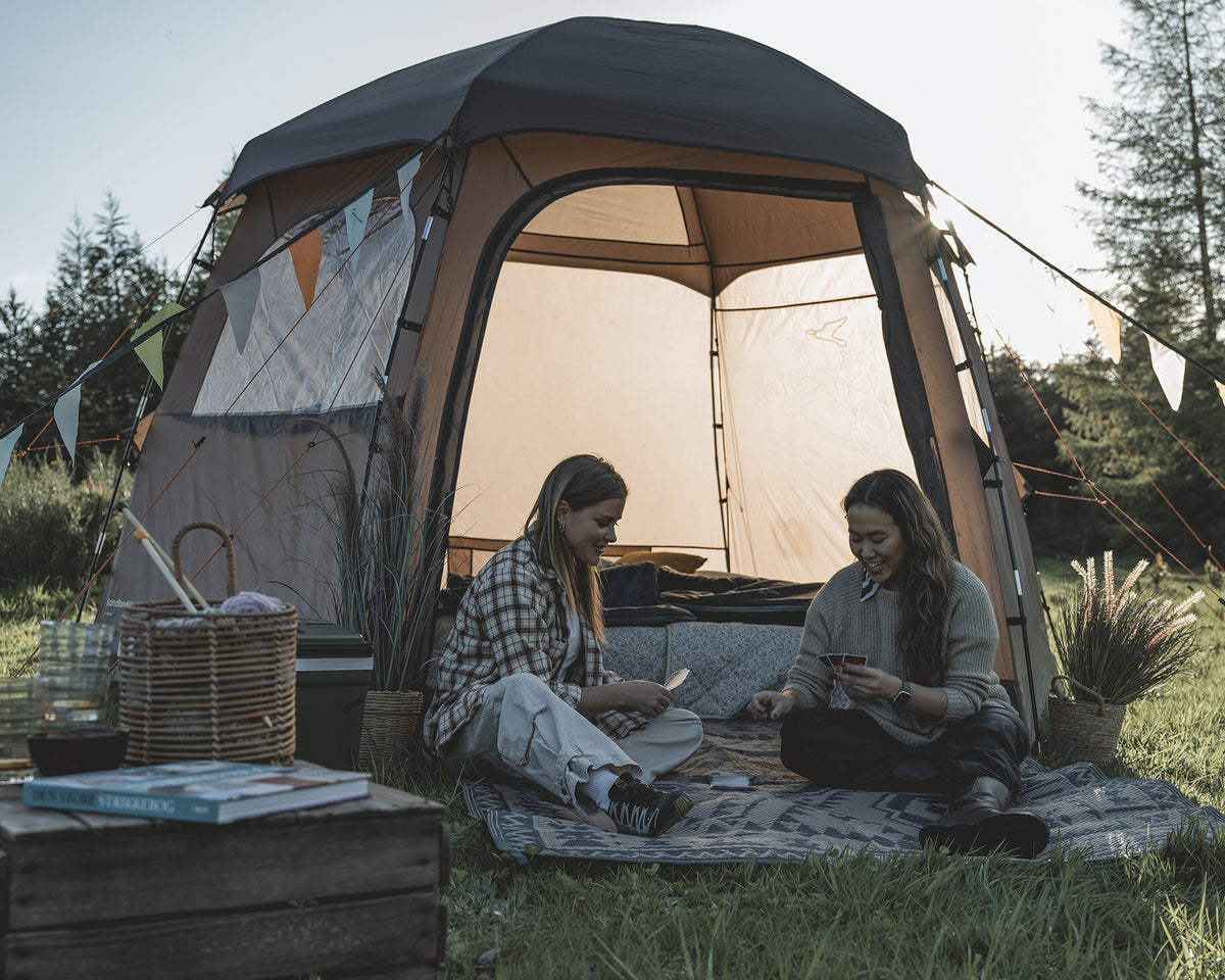 Two people sitting outside a tent in a natural setting
