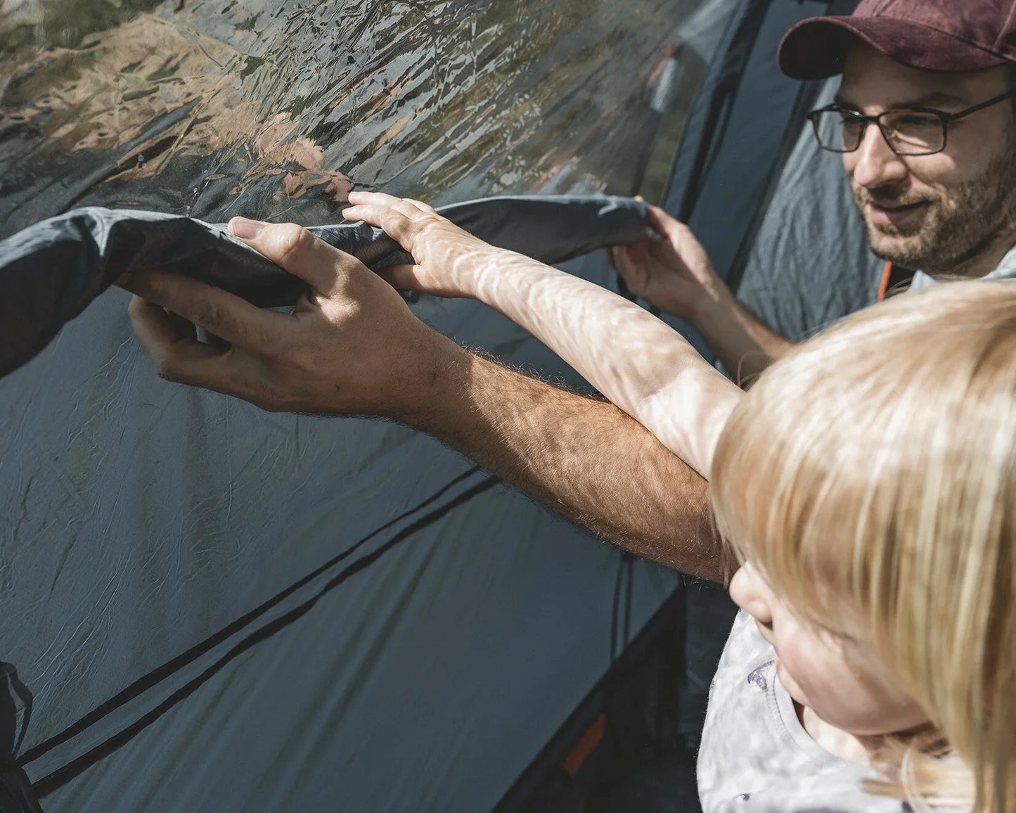 Father and child setting up a camping tent outdoors