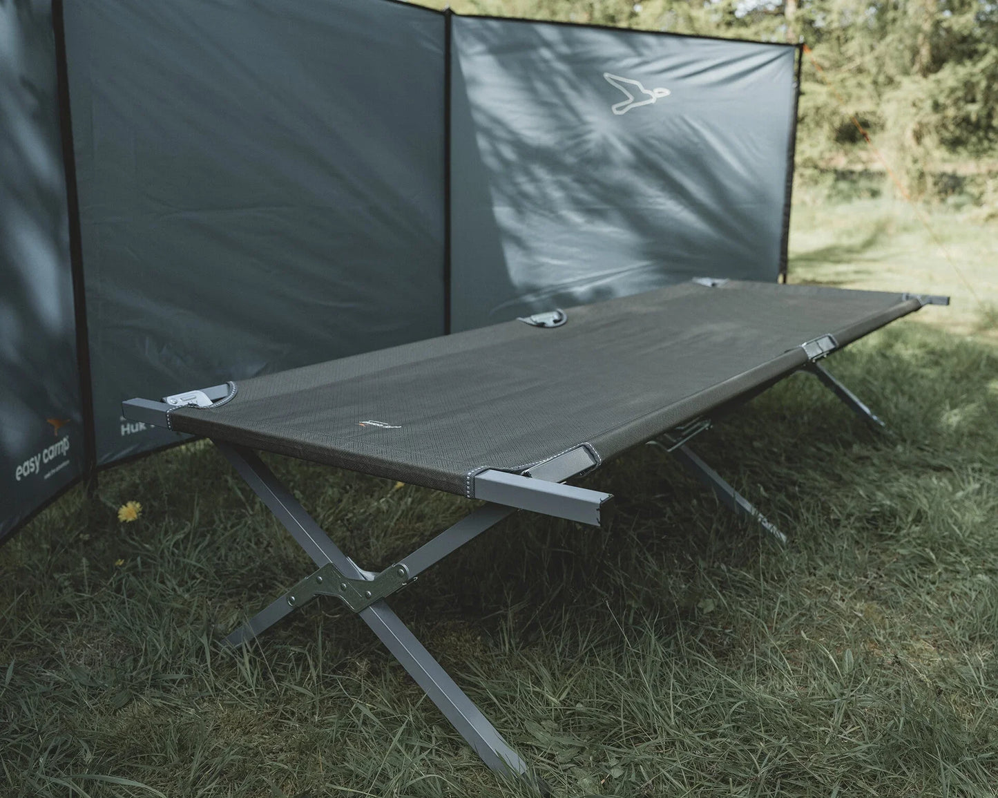 Portable camping cot with privacy screen on grassy outdoor setting