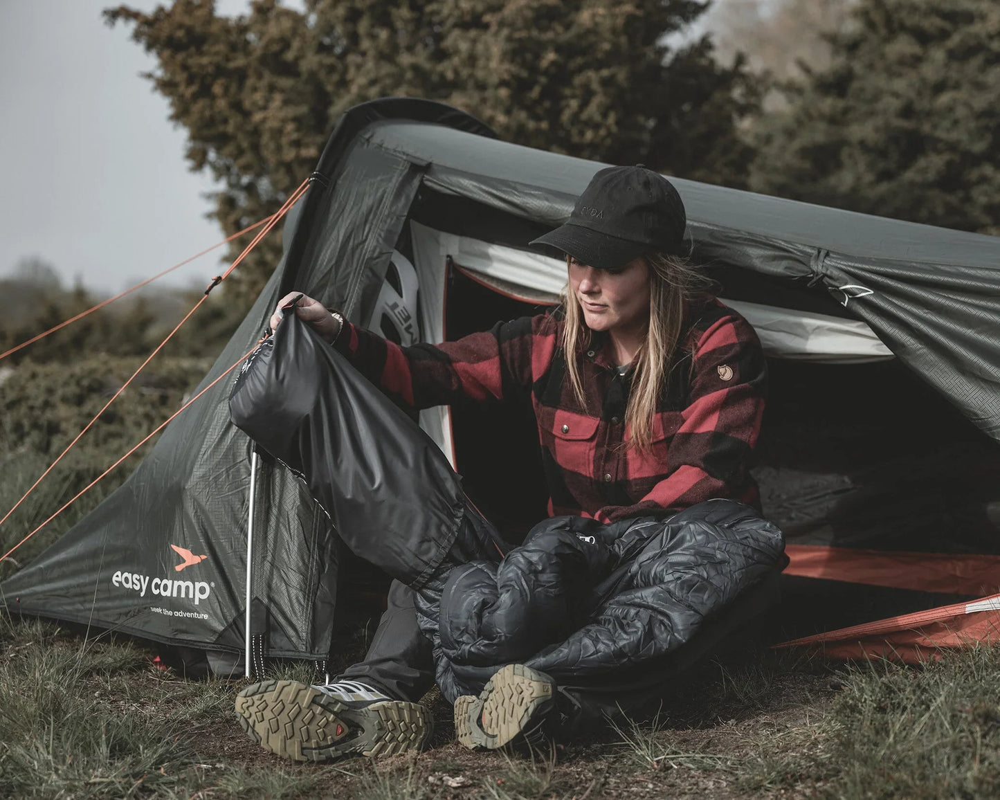 Woman packing sleeping bag near easy camp tent outdoors for camping adventure