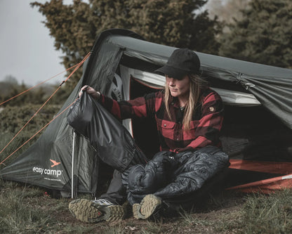Woman packing sleeping bag near easy camp tent outdoors for camping adventure