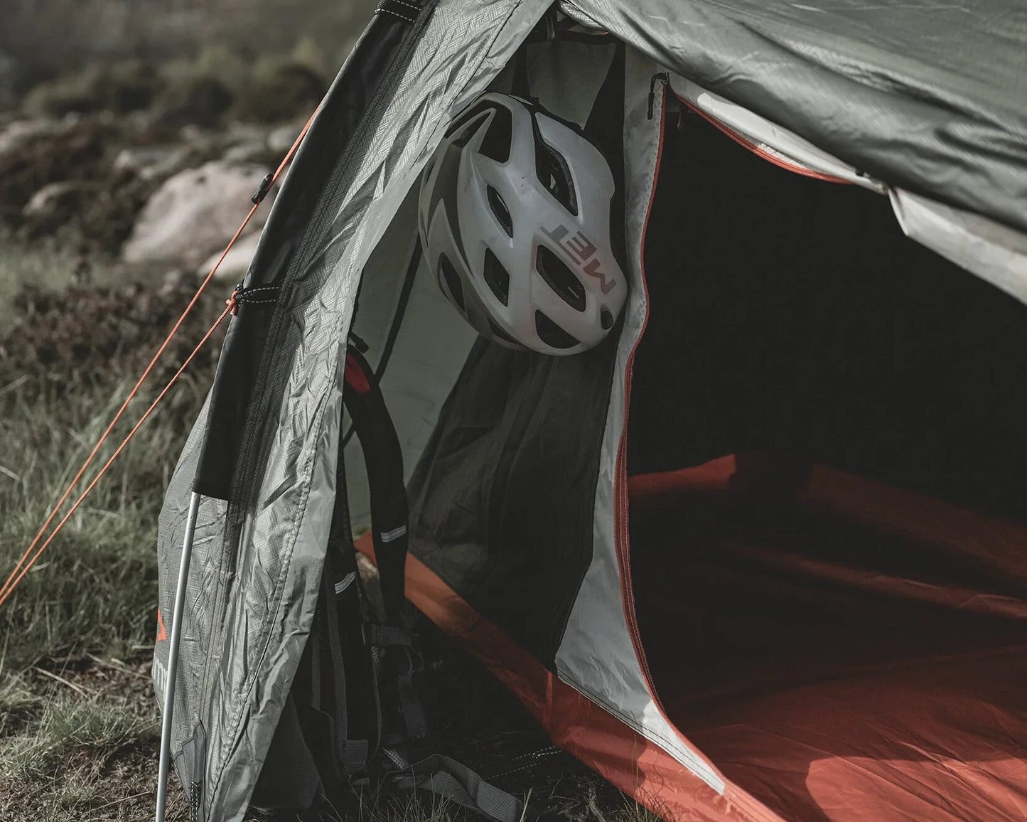 Camping tent with white helmet inside, outdoor adventure gear ready for use