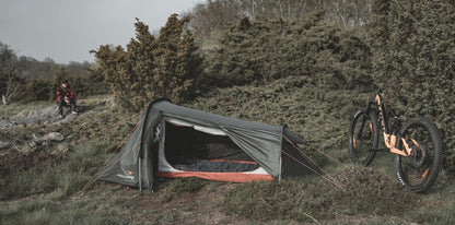 Gray and orange camping tent with mountain bike in outdoor setting