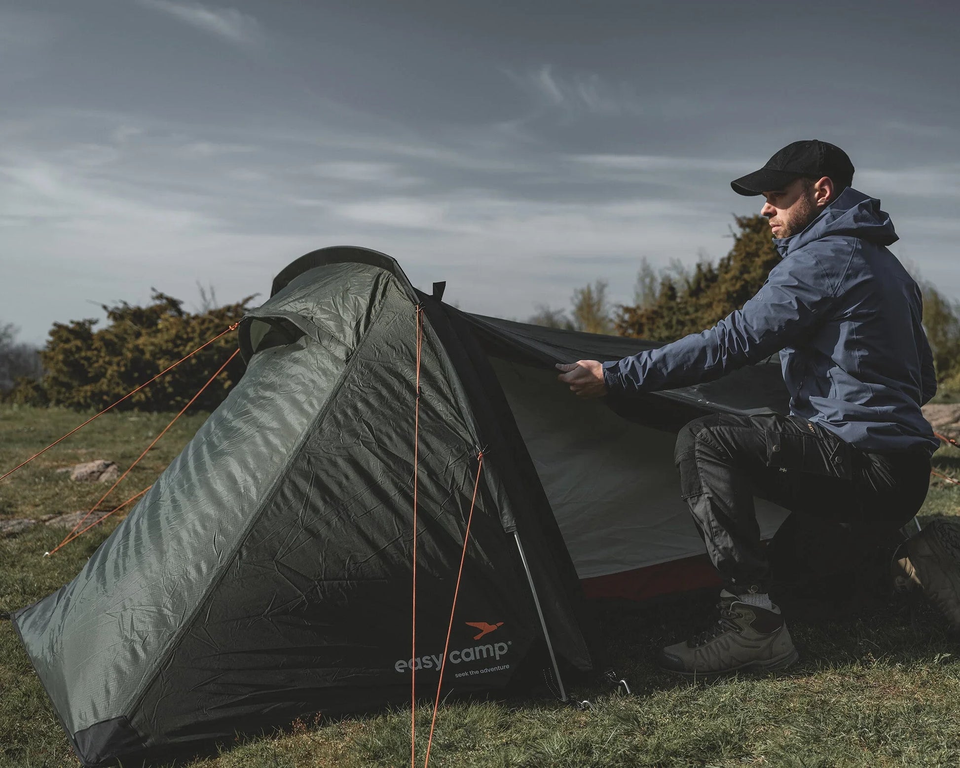 Man setting up a green Easy Camp tent outdoors for camping adventure