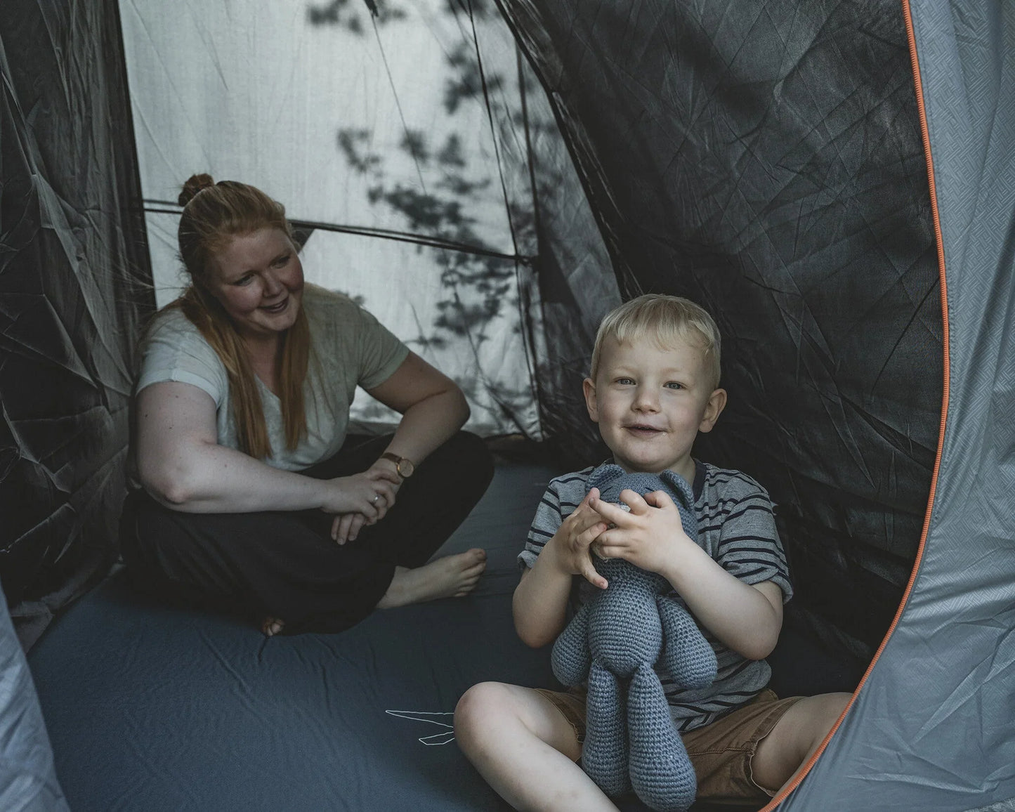 Mother and child enjoying cozy moments inside a camping tent with sleeping gear