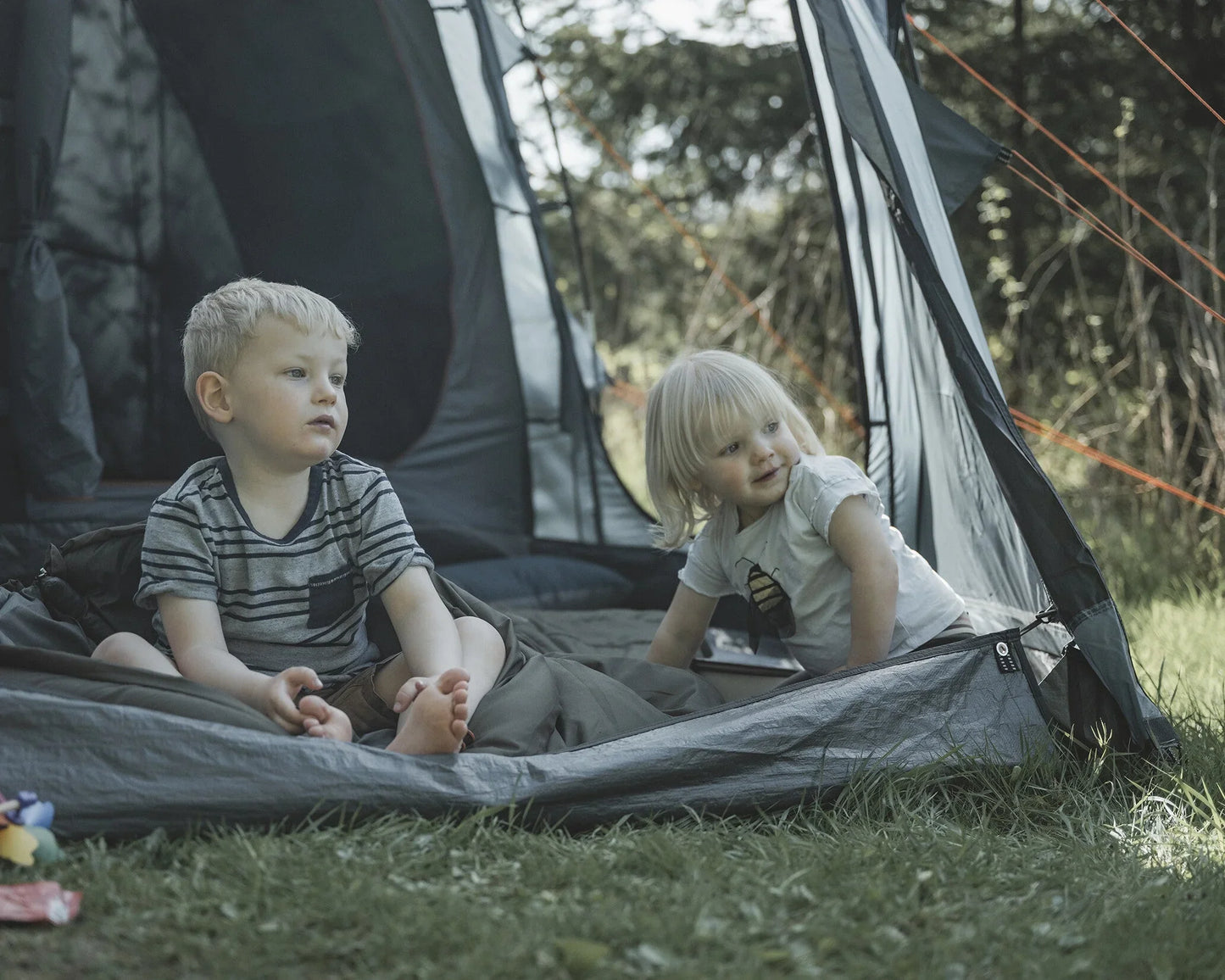 Kids enjoying camping in a tent with outdoor gear and sleeping bags
