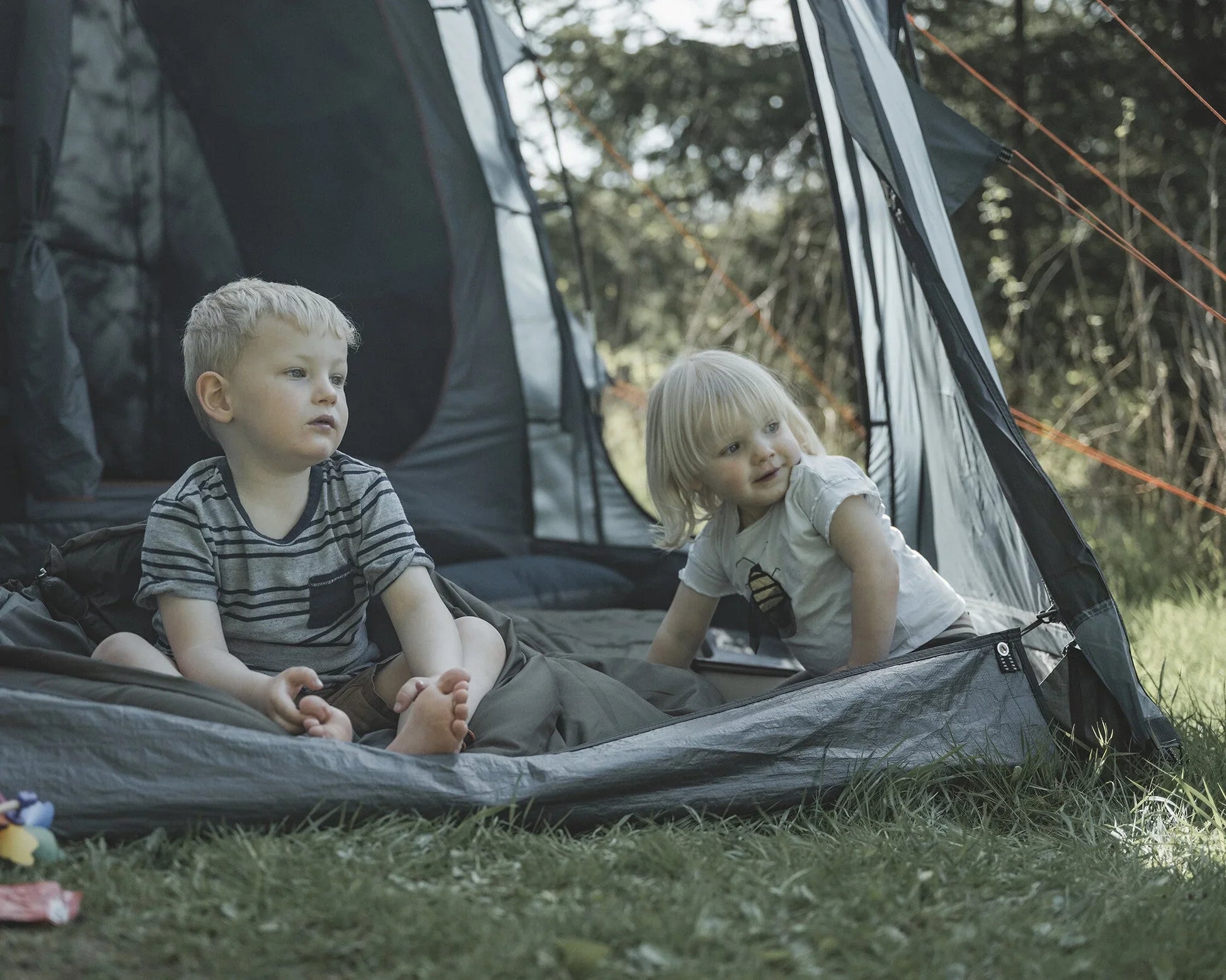 Kids enjoying camping in a tent with outdoor gear and sleeping bags