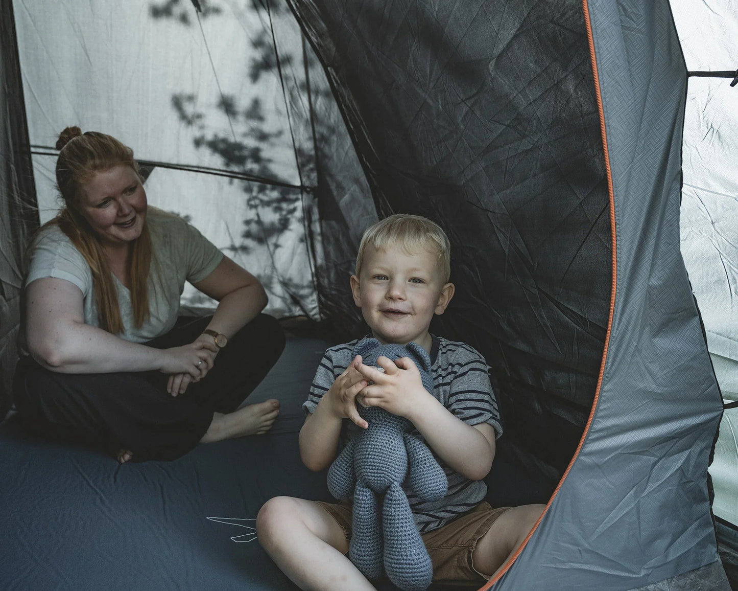 Family camping inside a tent with child holding stuffed toy, perfect for outdoor adventures and family trips.