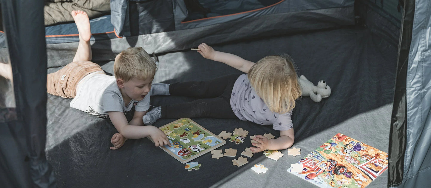 Kids playing with puzzles inside a camping tent, enjoying outdoor family fun.