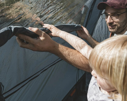 Father and child setting up a camping tent together outdoors
