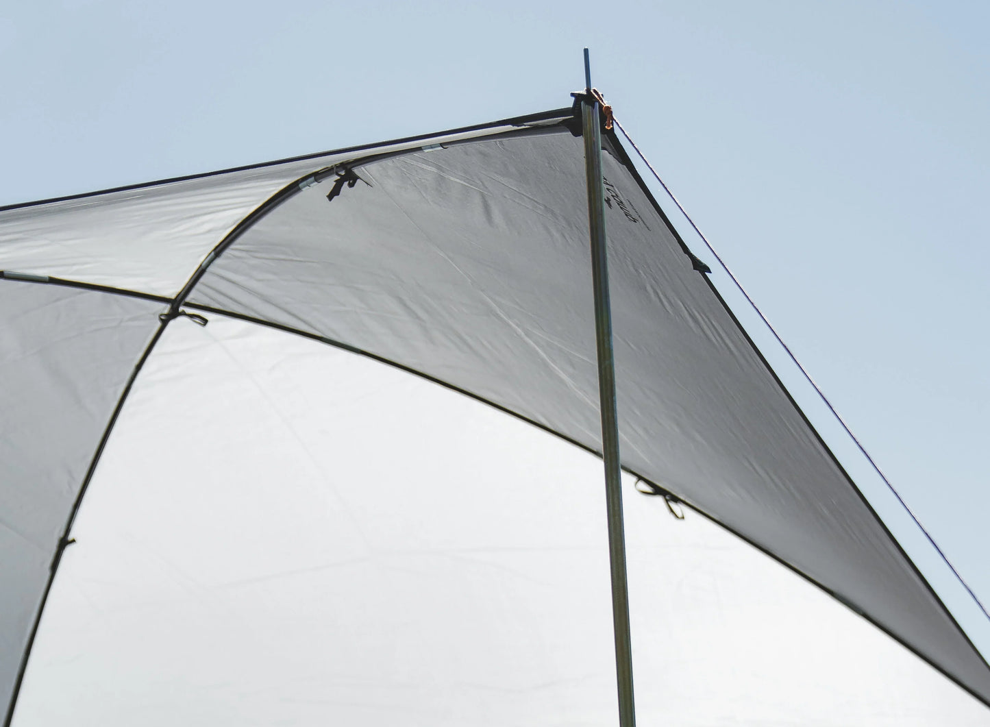 Gray camping awning with sturdy poles under clear sky