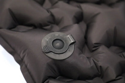 Close-up of black inflatable camping mattress with air valve for outdoor adventures