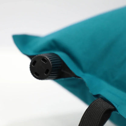 Teal camping pillow with black inflation valve and strap for outdoor adventures