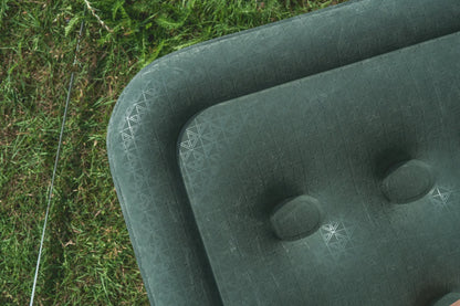 Green outdoor camping chair with textured pattern on grass