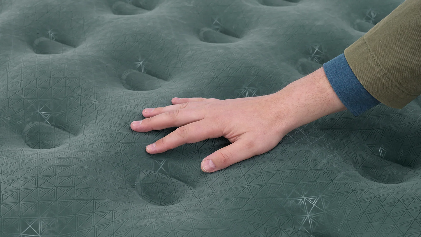 Hand pressing on green camping mattress with geometric pattern for outdoor comfort