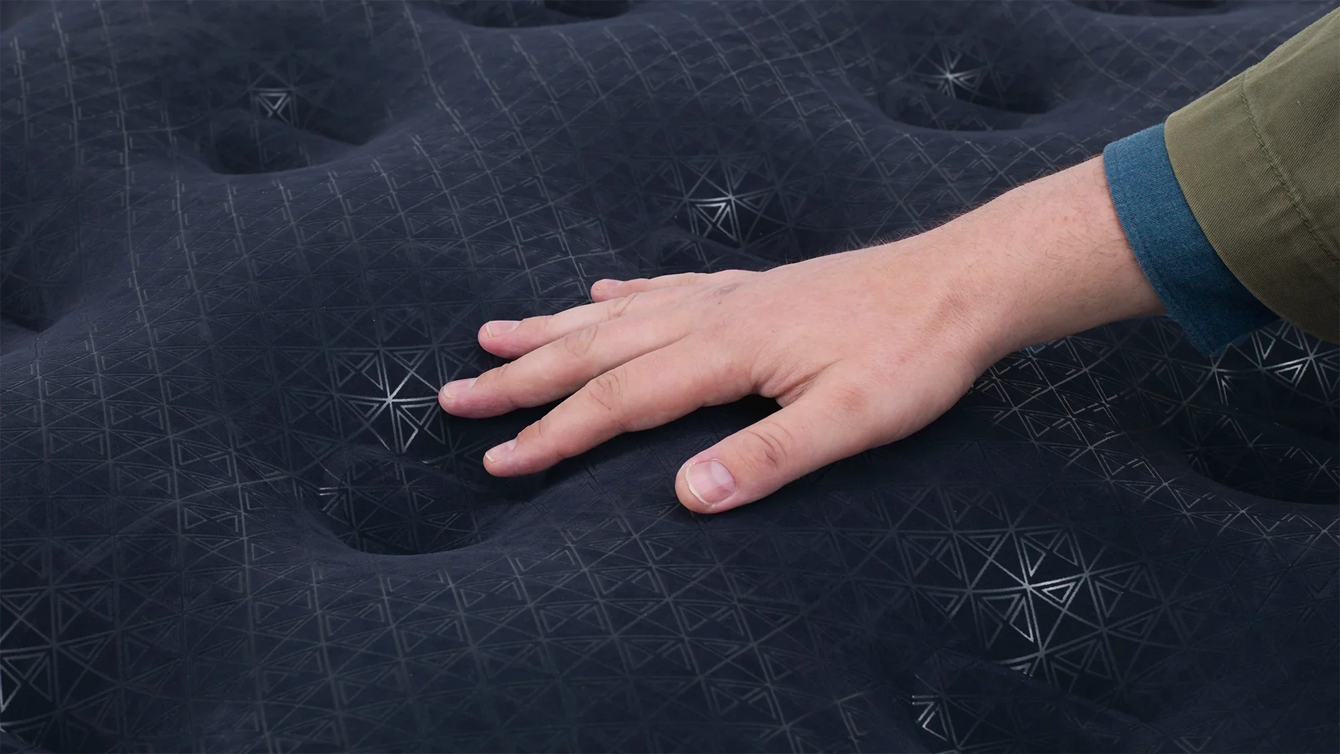 Hand pressing on black camping mattress with geometric pattern for outdoor comfort