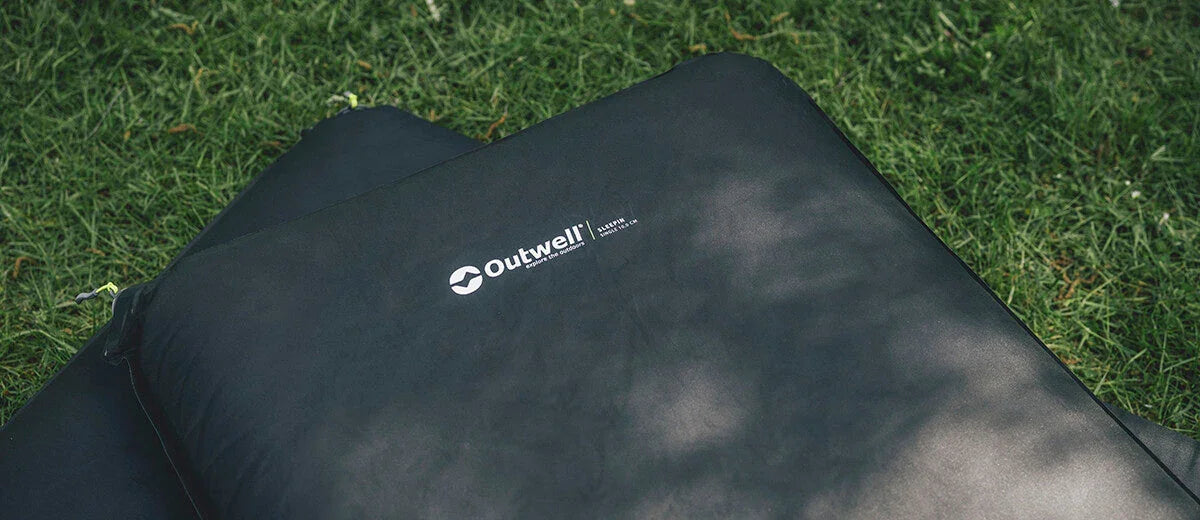 Outwell camping sleeping pad on grass, ideal for outdoor adventures and comfortable rest.