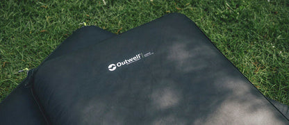 Outwell camping sleeping pad on grass, ideal for outdoor adventures and comfortable rest.