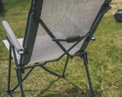 Portable camping chair with mesh back and armrests on grass, ideal for outdoor adventures and camping trips.