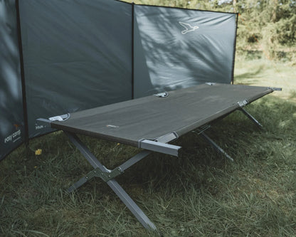 Portable camping cot with privacy screen on grassy outdoor setting