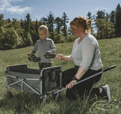 Woman and child with portable camping wagon in grassy outdoor setting