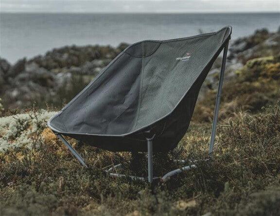 Portable camping chair on rocky terrain near ocean, ideal for outdoor adventures and relaxation.