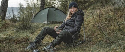 Woman camping with tent and chair in outdoor setting, enjoying nature adventure gear