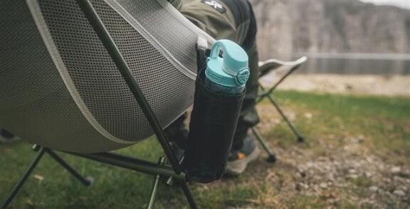 Camping chair with mesh side pocket holding water bottle, ideal for outdoor adventures and caravanning trips.