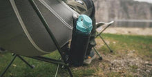 Camping chair with mesh side pocket holding water bottle, ideal for outdoor adventures and caravanning trips.
