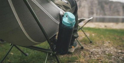 Camping chair with mesh side pocket holding water bottle, ideal for outdoor adventures and caravanning trips.