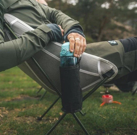 Camping chair with side pocket holding water bottle, ideal for outdoor adventures and caravanning trips.
