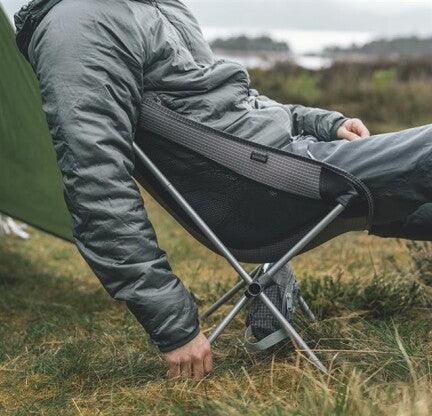 Portable camping chair with person relaxing outdoors near tent
