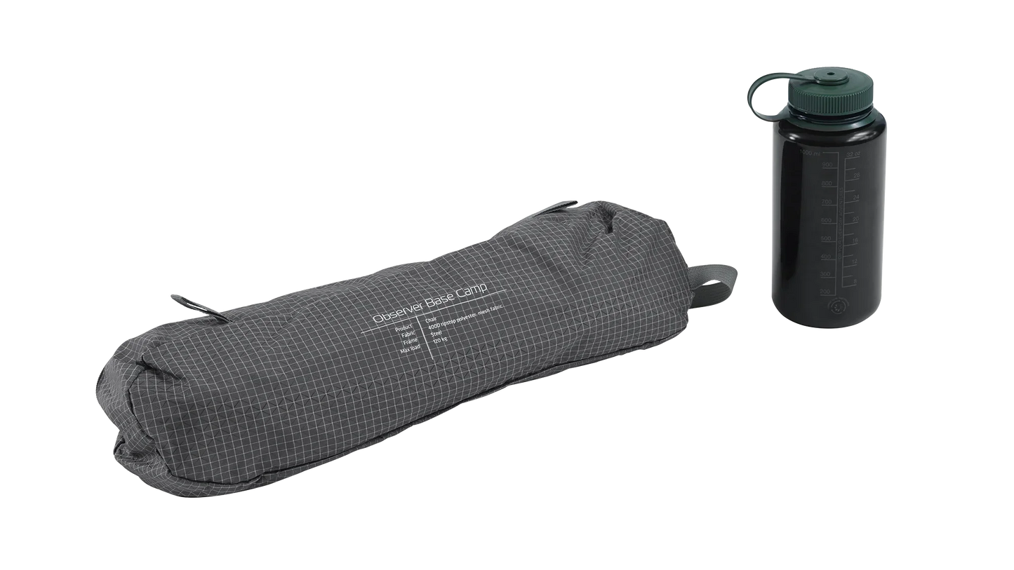 Compact Observer Base Camp camping chair in carry bag with water bottle, ideal for outdoor adventures and caravanning.