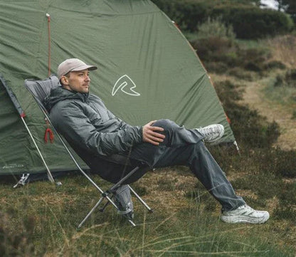 Man relaxing in camping chair beside green tent outdoors