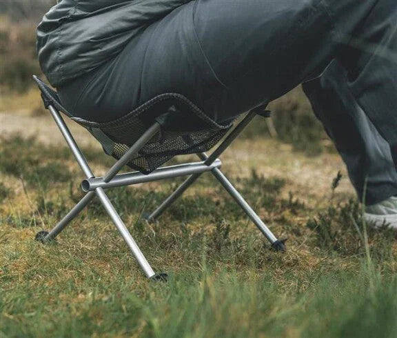 Portable camping chair with mesh seat and aluminum frame on grass, ideal for outdoor adventures