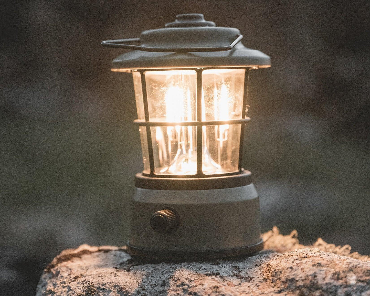 Portable camping lantern glowing warmly on a rock, perfect for outdoor adventures and nighttime camping.