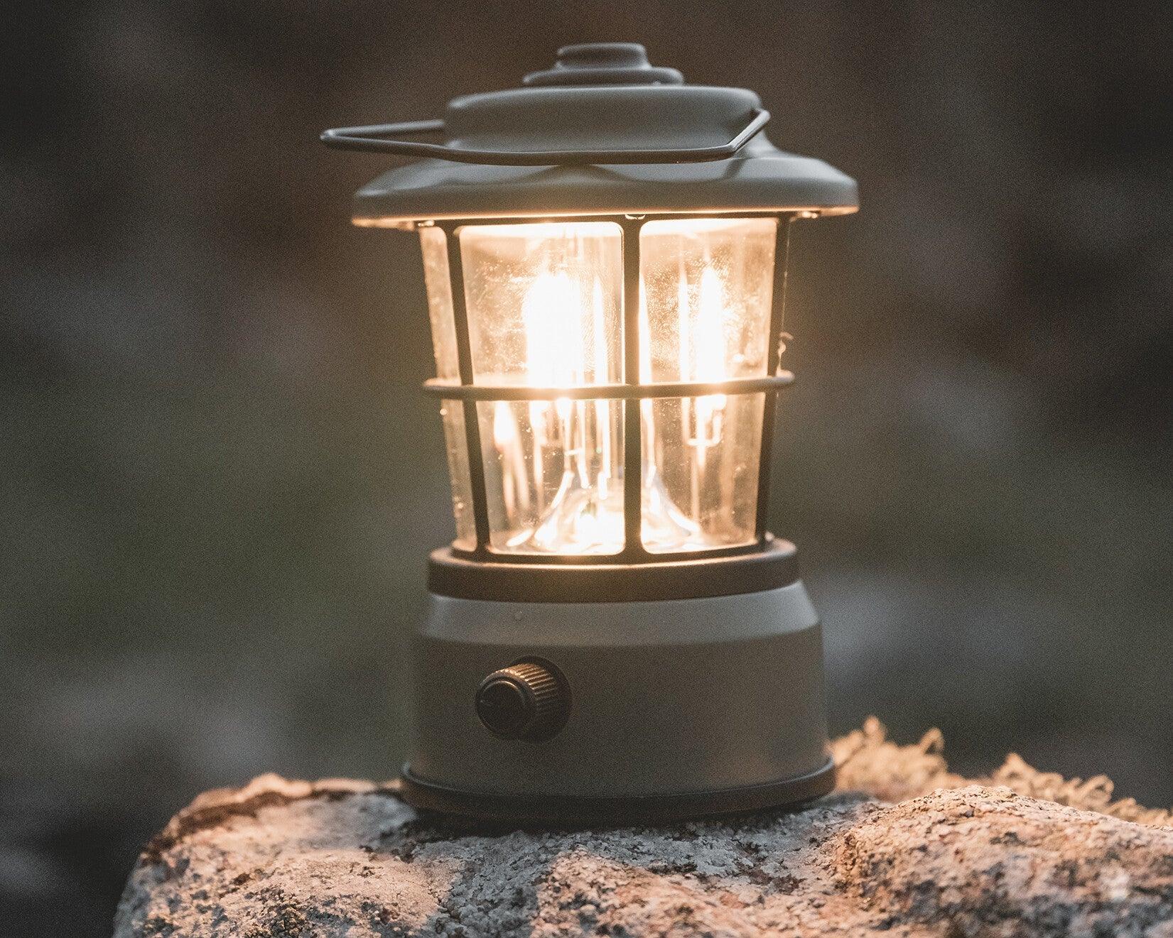 Portable camping lantern glowing warmly on a rock, perfect for outdoor adventures and nighttime camping.