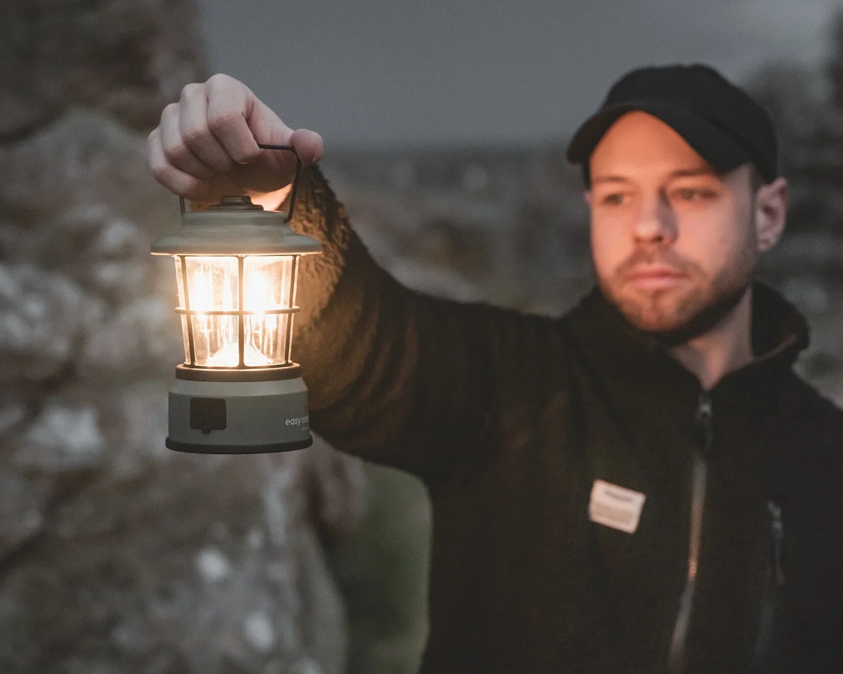 Man holding illuminated camping lantern outdoors for nighttime adventures