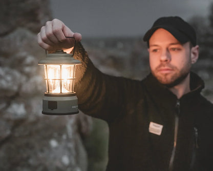 Man holding illuminated camping lantern outdoors for nighttime adventures