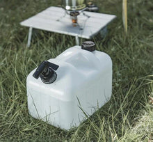 White portable fuel container for camping with outdoor cooking setup on grass