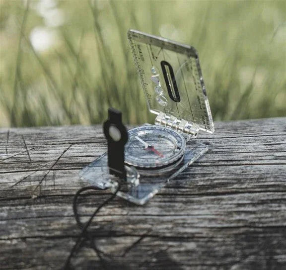 Clear compass on wooden surface for outdoor navigation and camping adventures