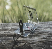 Clear compass on wooden surface for outdoor navigation and camping adventures