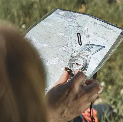 Hiker using compass and map for outdoor navigation during camping adventure
