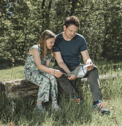 Father and daughter reading map outdoors, enjoying camping adventure in nature