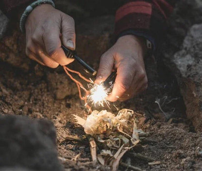 Hands lighting a campfire with fire starter tools for outdoor camping adventures