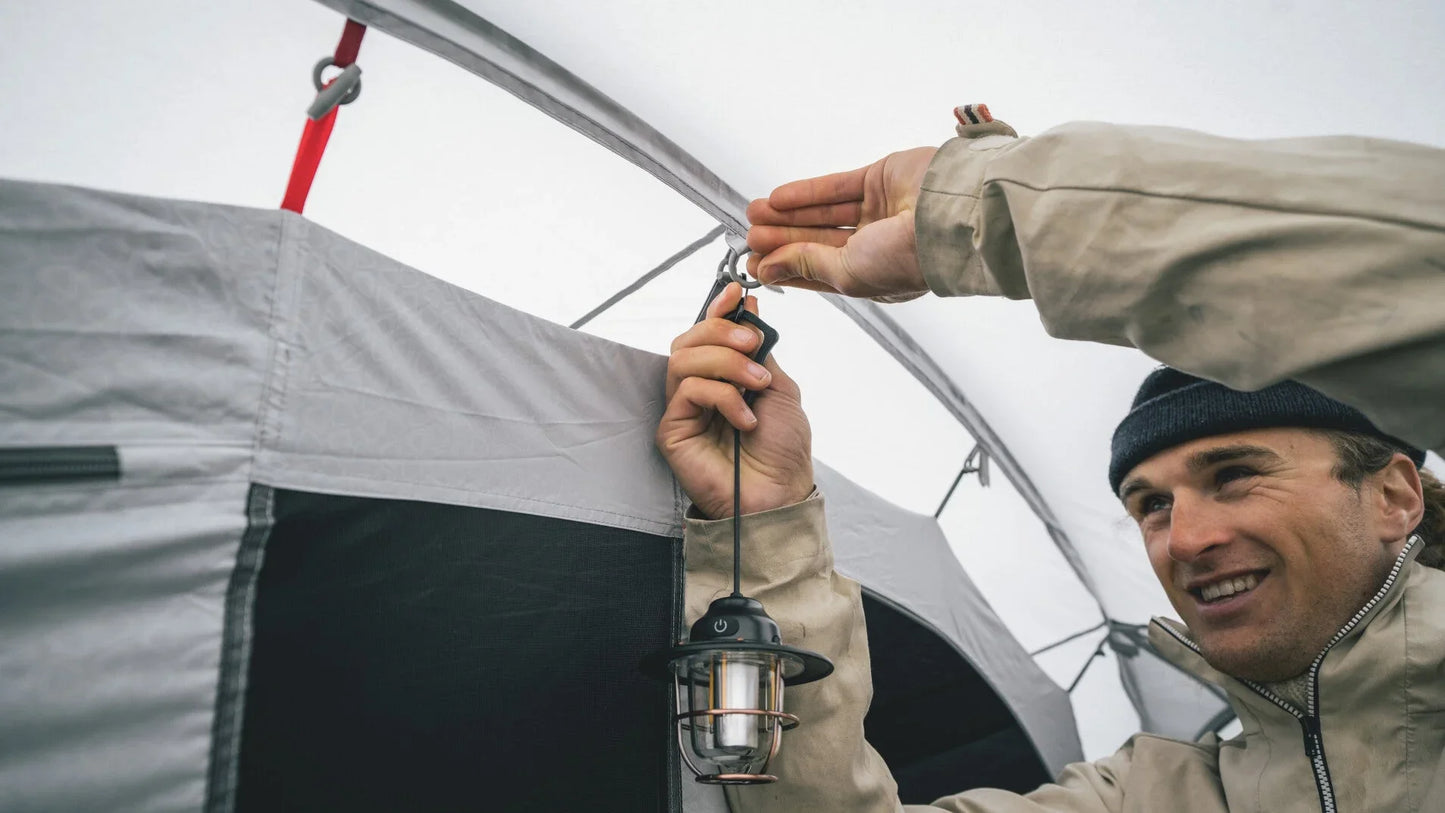 Man hanging camping lantern inside tent for outdoor adventure lighting