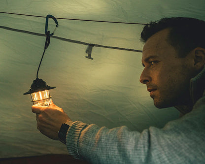 Man holding glowing camping lantern inside tent, ideal for outdoor adventures and camping gear