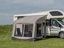 Motorhome awning with mesh windows and outdoor furniture on grassy field