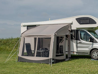 Motorhome awning with mesh windows and outdoor furniture on grassy field