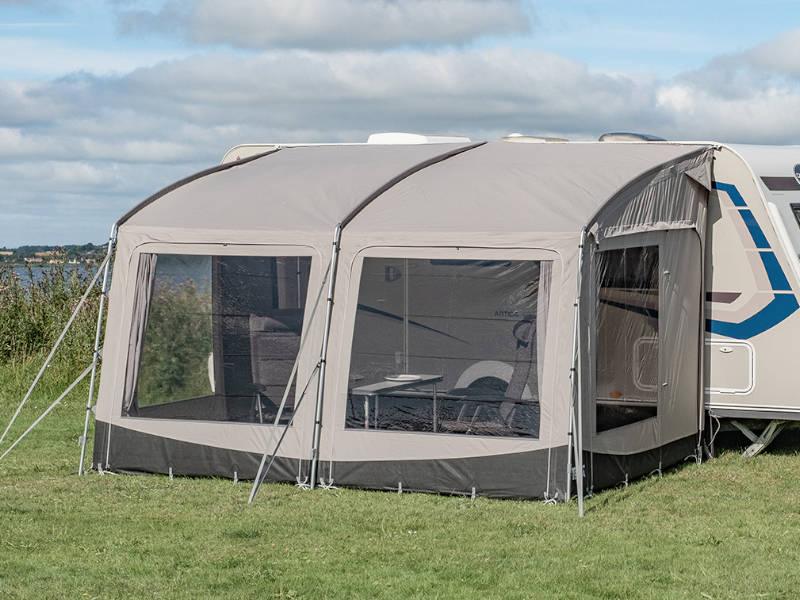 Beige caravan awning with mesh windows set up on grass, ideal for camping and outdoor adventures.